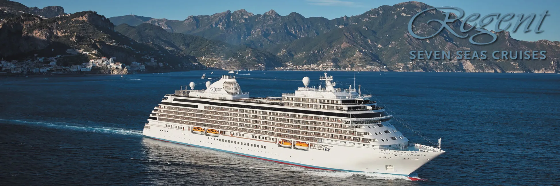 Regent Seven Seas cruise ship sailing along scenic mountainous coastline