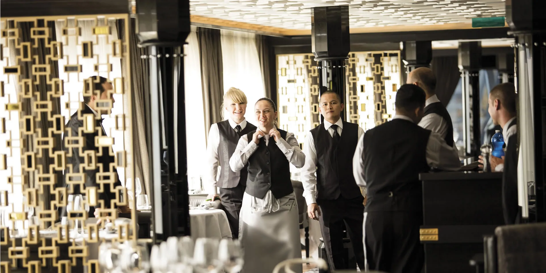 Restaurant staff in black and white uniforms prepare for service