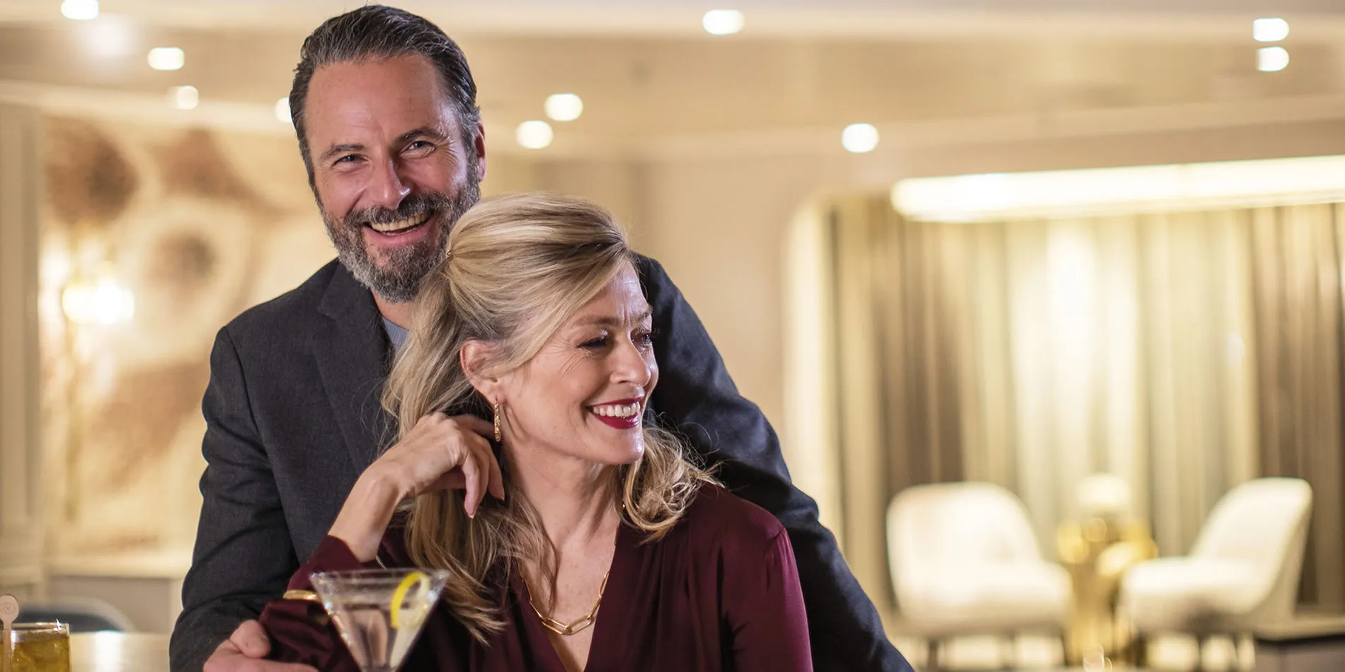 Elegant couple laughing together at a formal event with cocktails