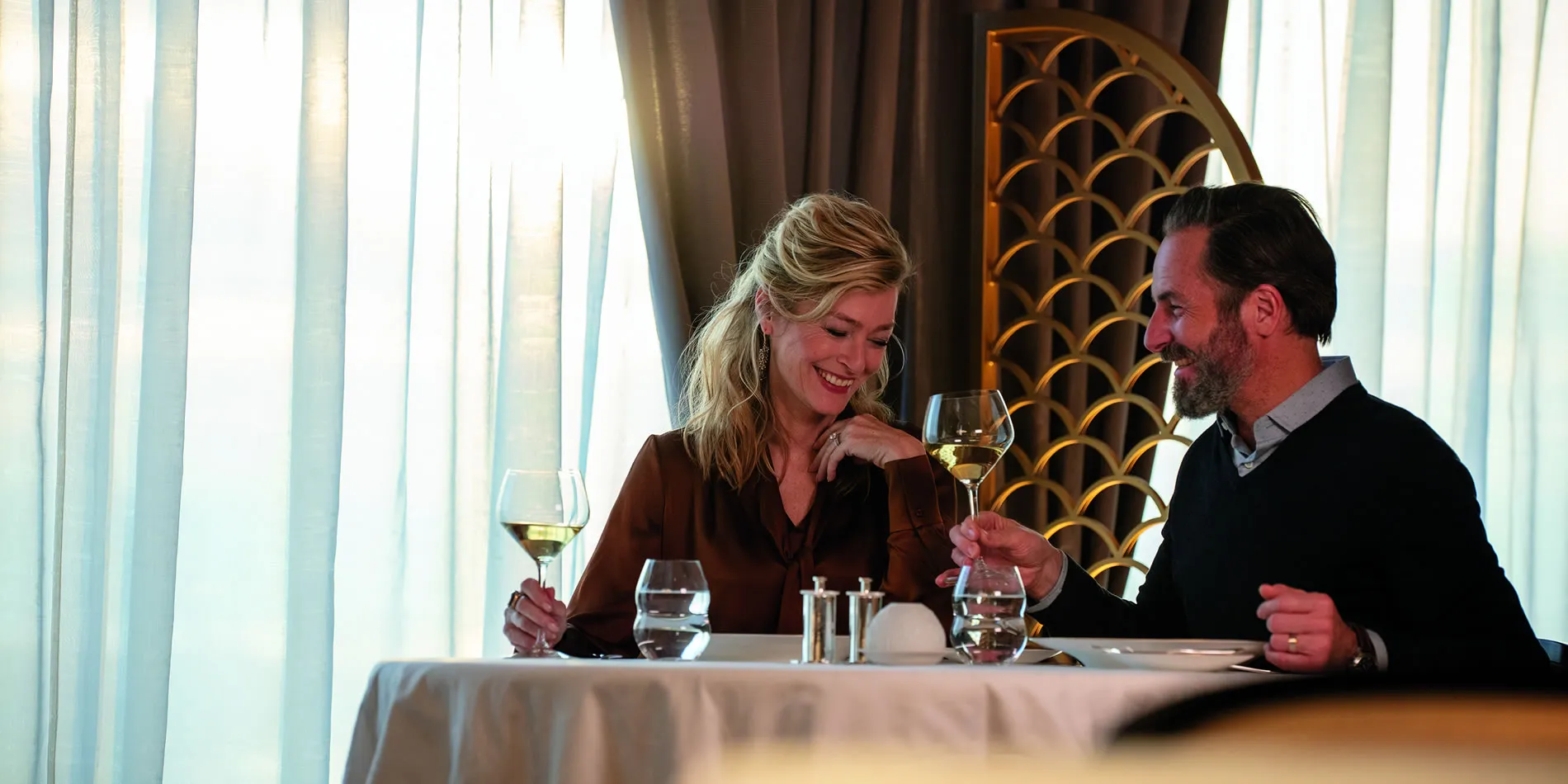 Two people enjoying white wine at an elegant restaurant table together