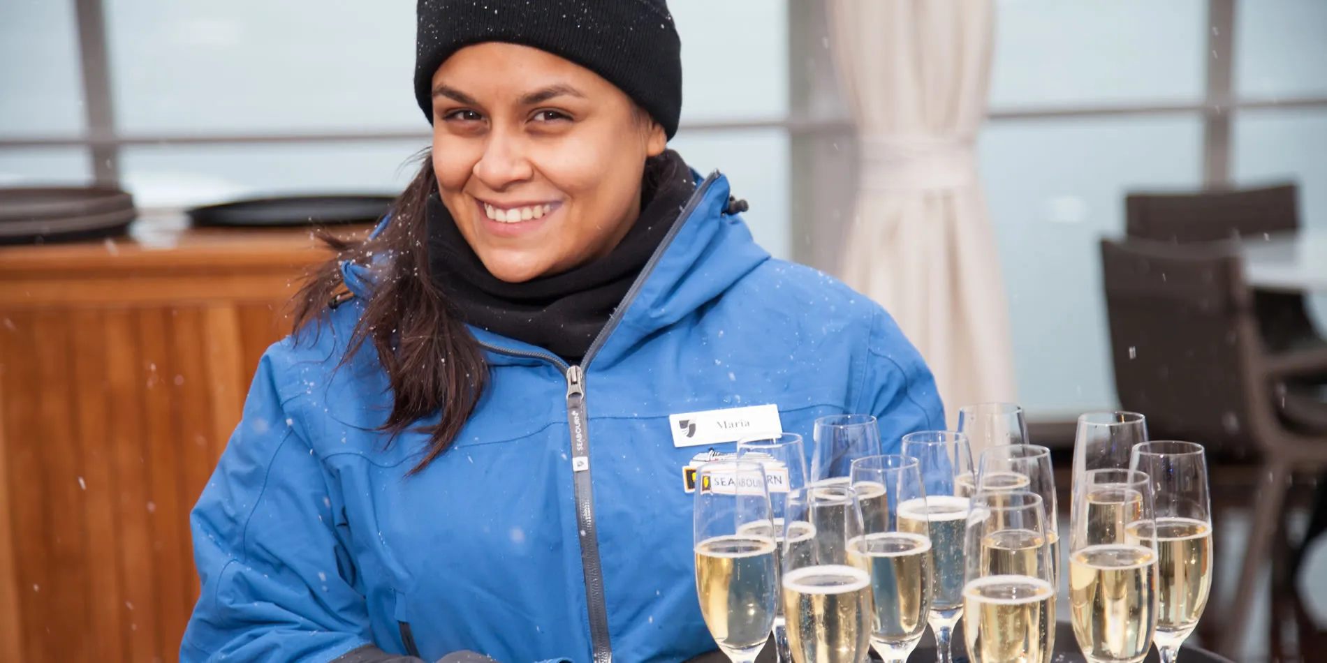 Smiling person in blue winter coat with champagne glasses