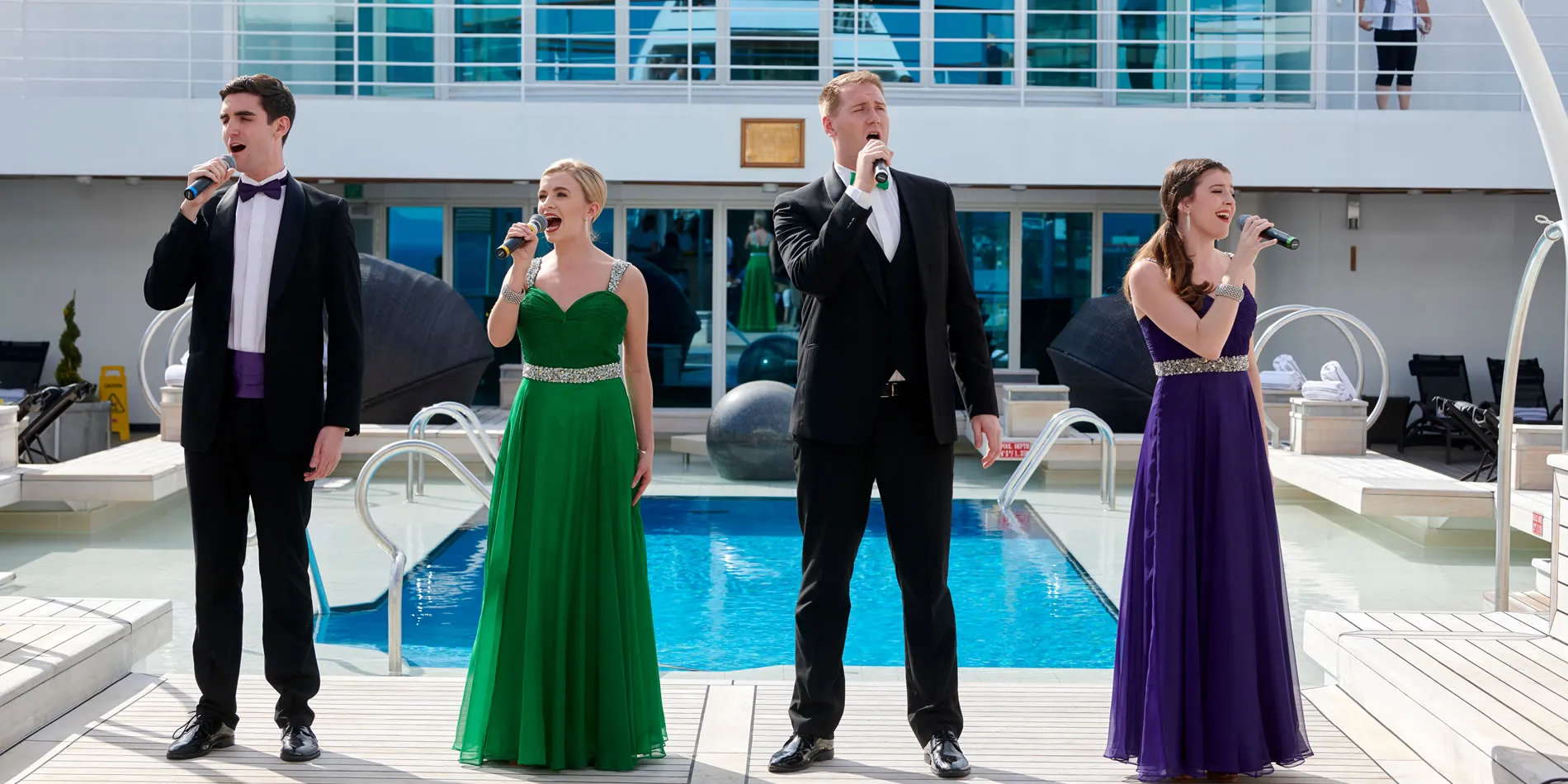 Four singers in formal attire performing by swimming pool on cruise ship