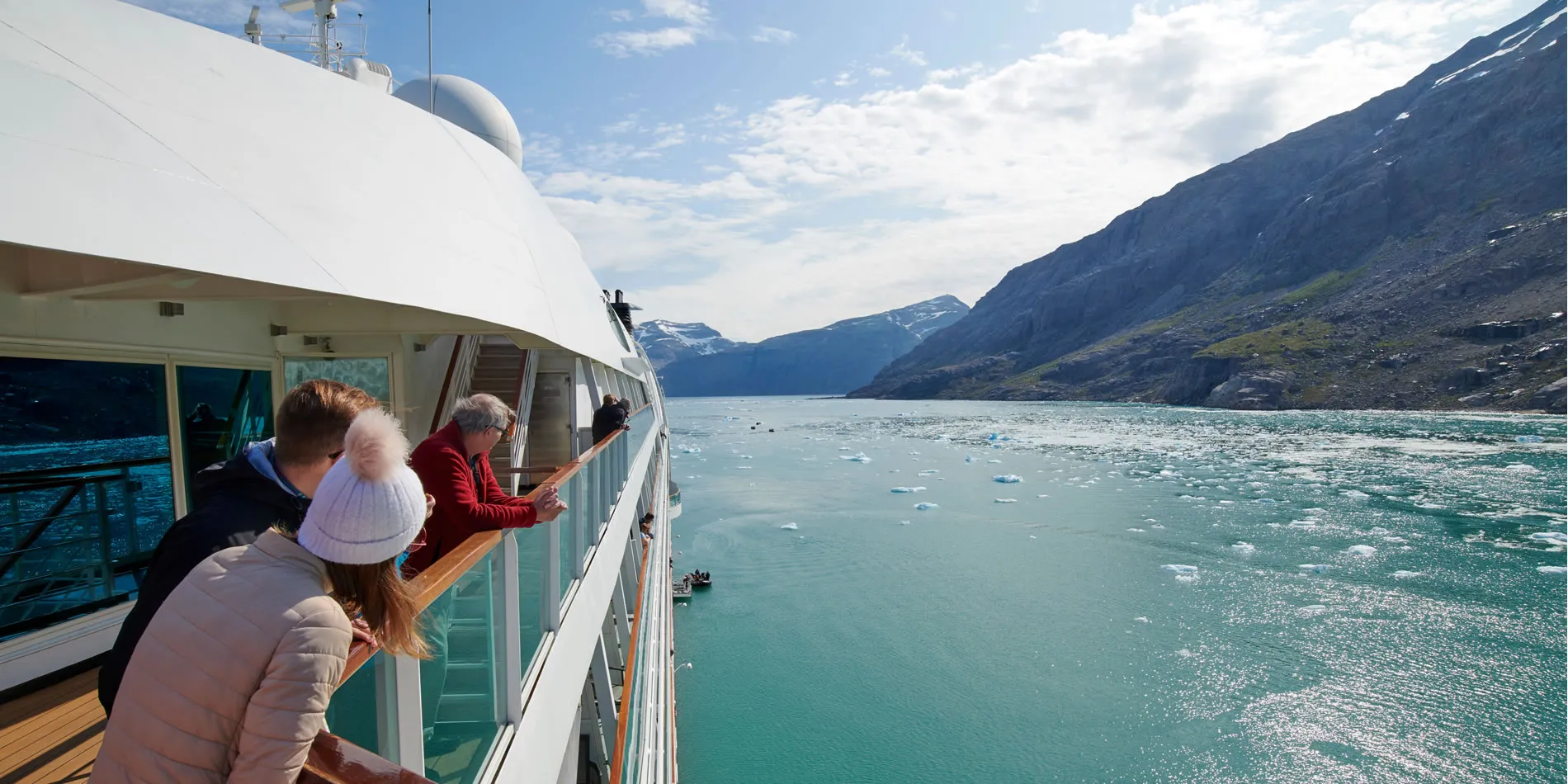 Cruise passengers view glacial landscape with floating ice from ship deck