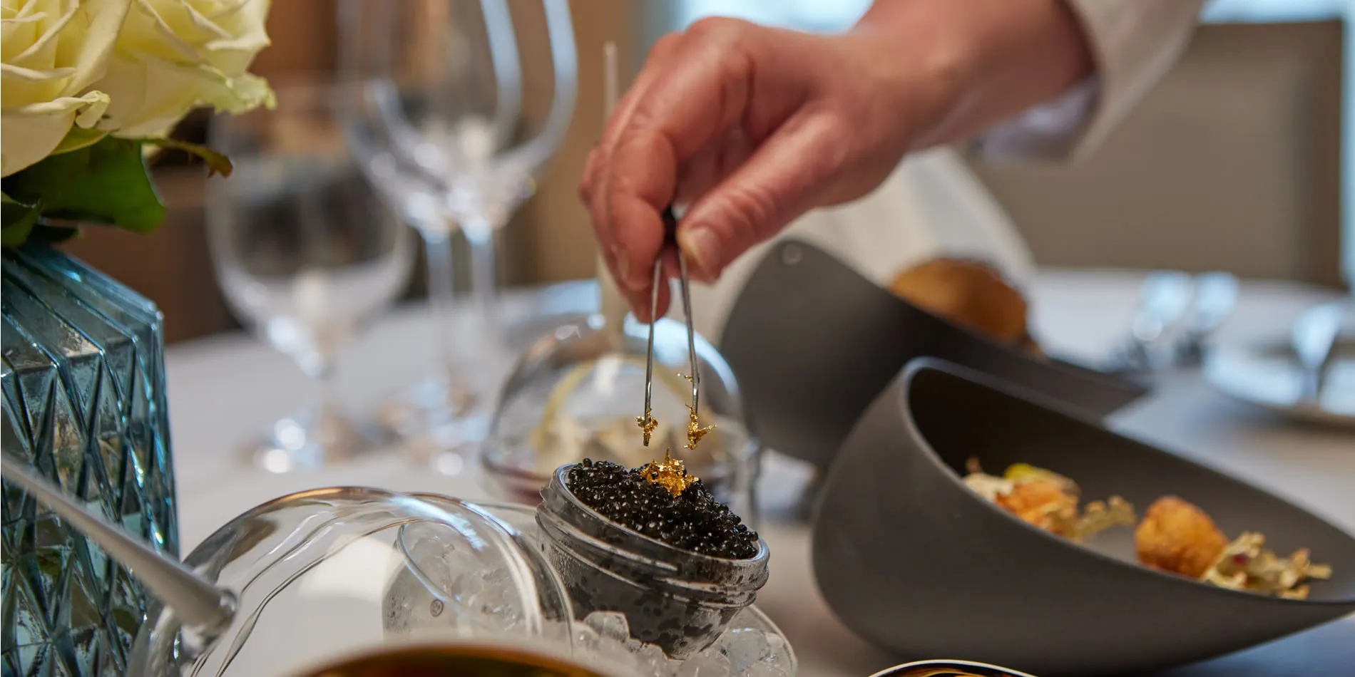Hand preparing caviar with golden garnish on elegant dining table