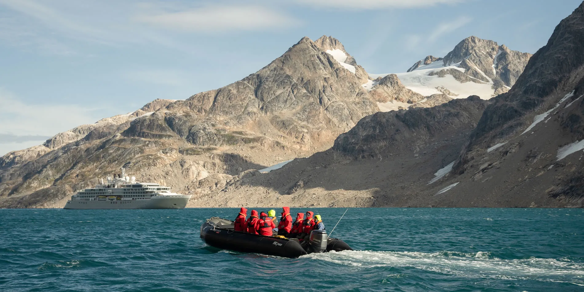 Zodiac boat with tourists exploring glacial waters near snowy mountain landscape