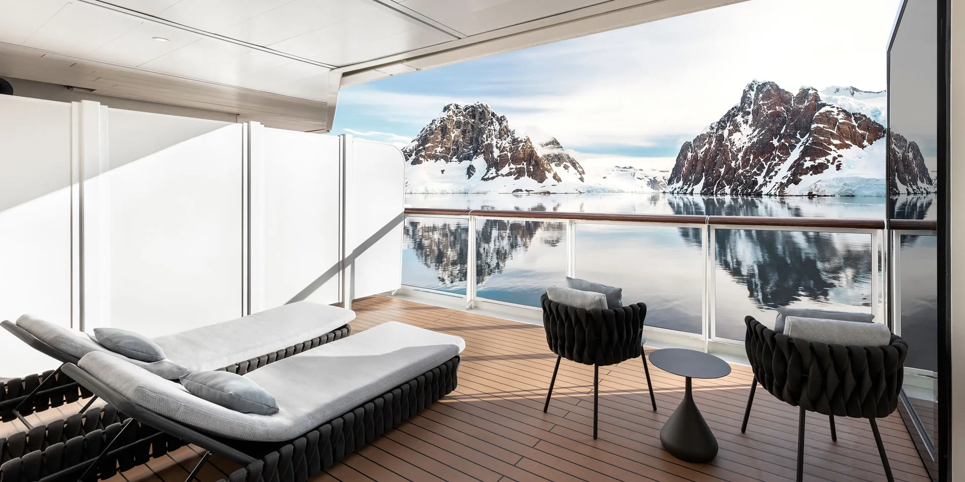 Luxury balcony with lounge chairs overlooking snowy Antarctic mountain landscape