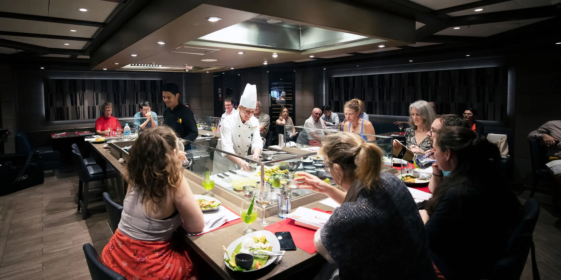 Cooking class with chef and participants around interactive kitchen counter