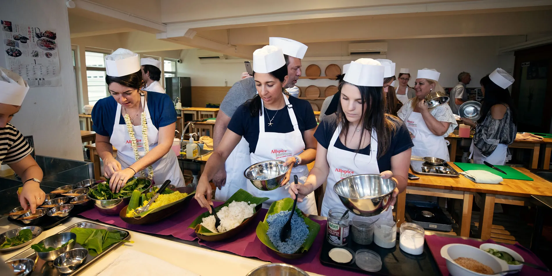 Cooking class with students in white hats preparing dishes with colorful ingredients