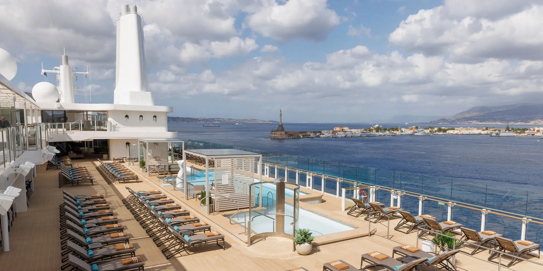 Luxurious cruise ship deck with pools overlooking Mediterranean harbor