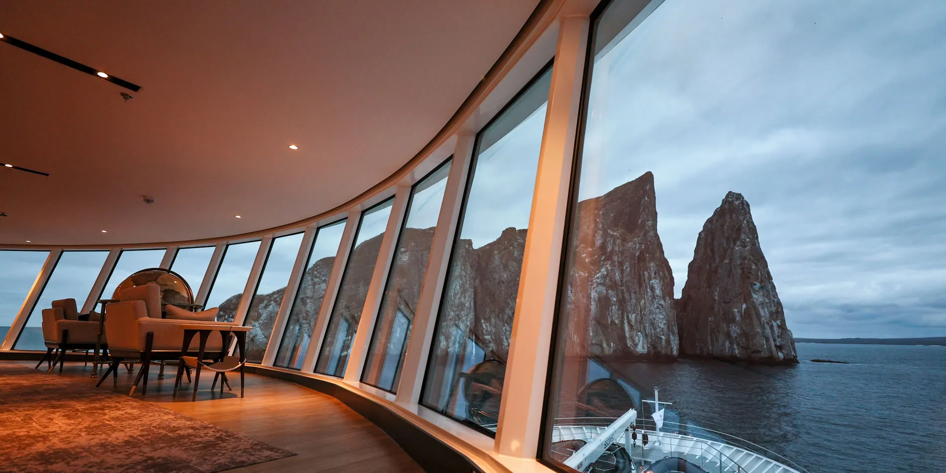 Cruise ship lounge with panoramic view of rocky sea stacks