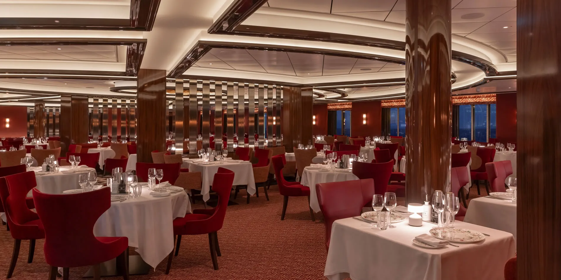 Elegant dining room with red chairs, white tablecloths, and wooden columns