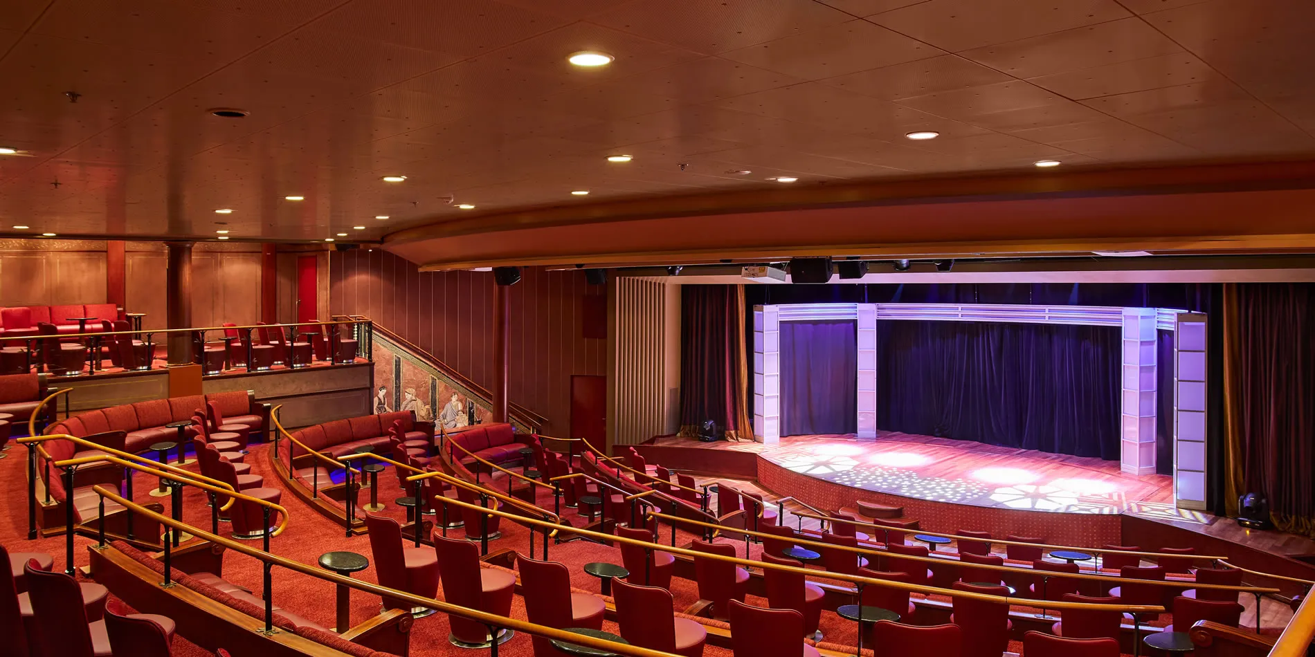 Empty theater with red seats, stage, and dramatic purple lighting