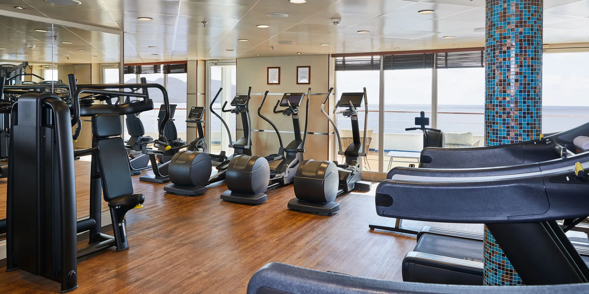 Cruise ship fitness center with exercise machines and ocean view