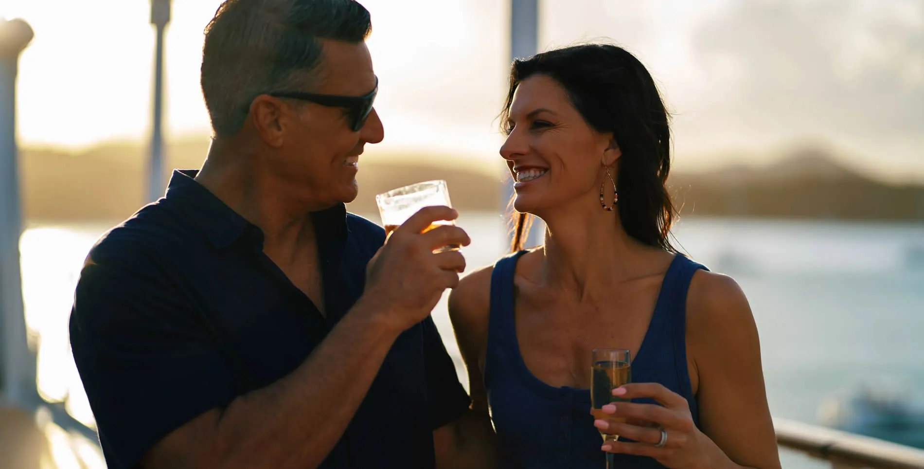 Couple enjoying drinks together at sunset, smiling and toasting