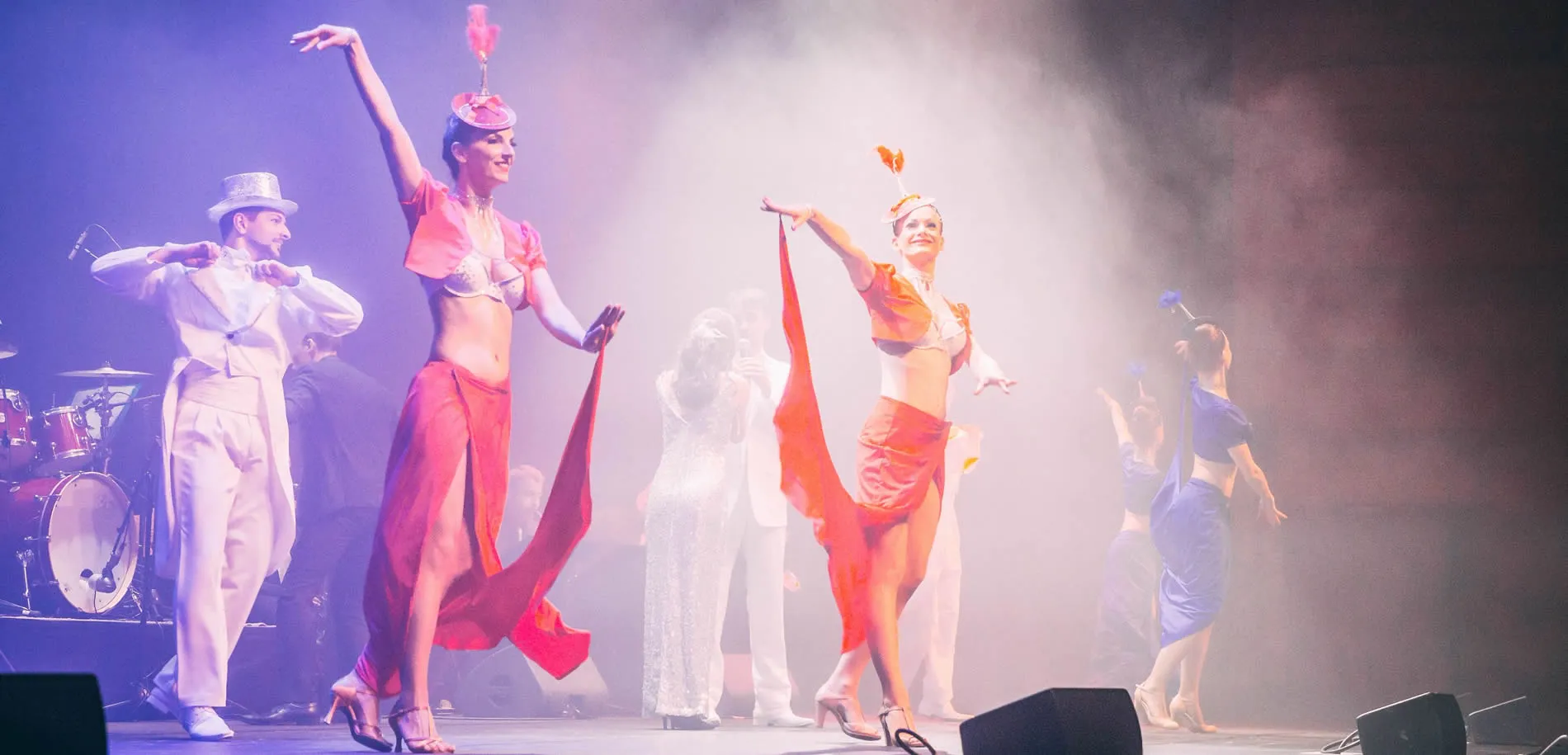 Theatrical dance performance with performers in vibrant costumes on smoky stage