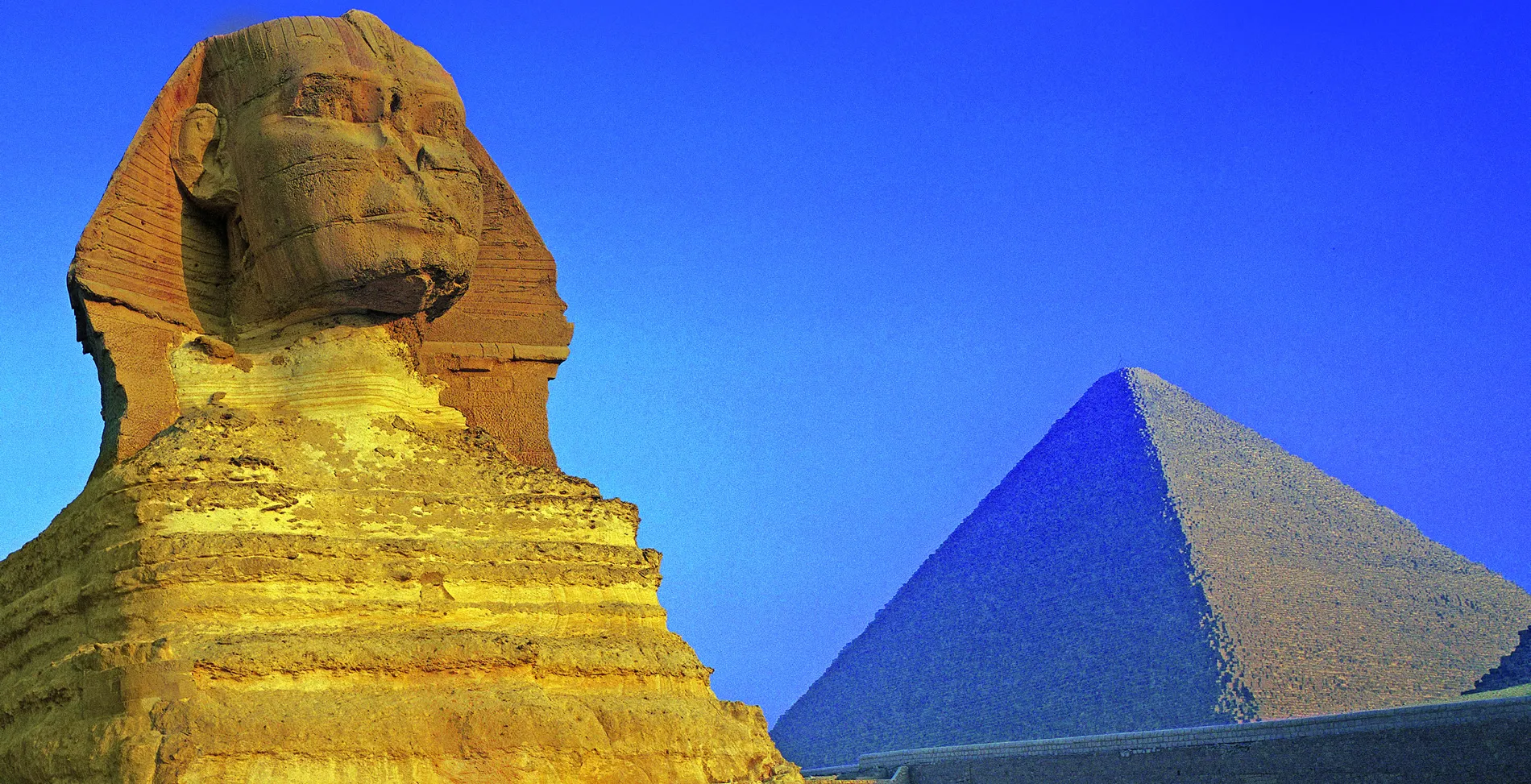 Great Sphinx and Pyramid of Giza against bright blue sky in Egypt