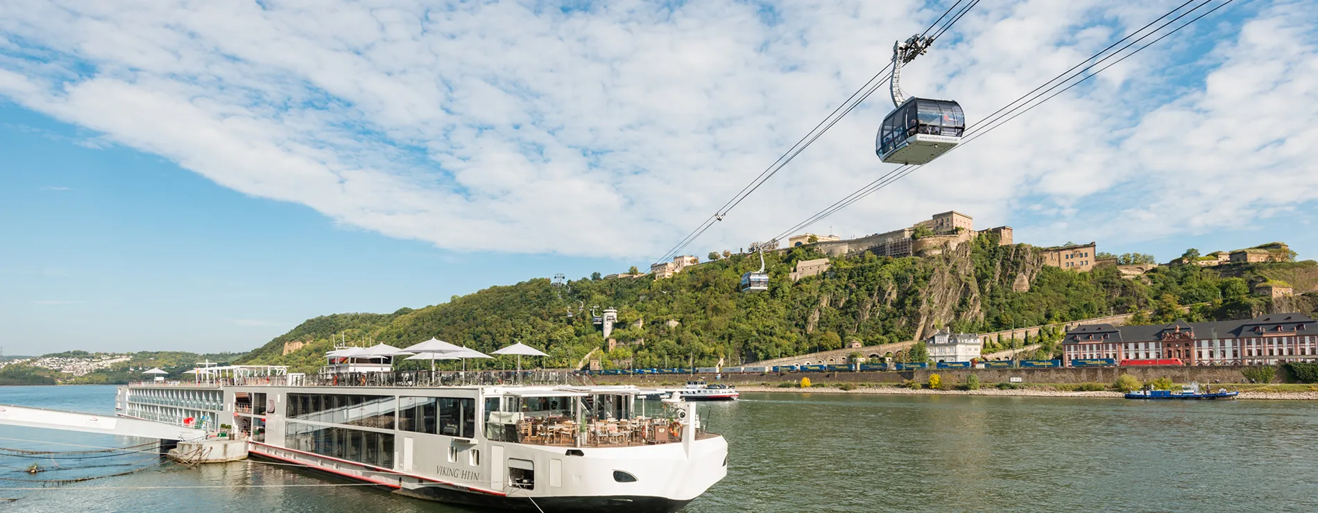 River cruise ship and cable cars along scenic riverbank with historic buildings