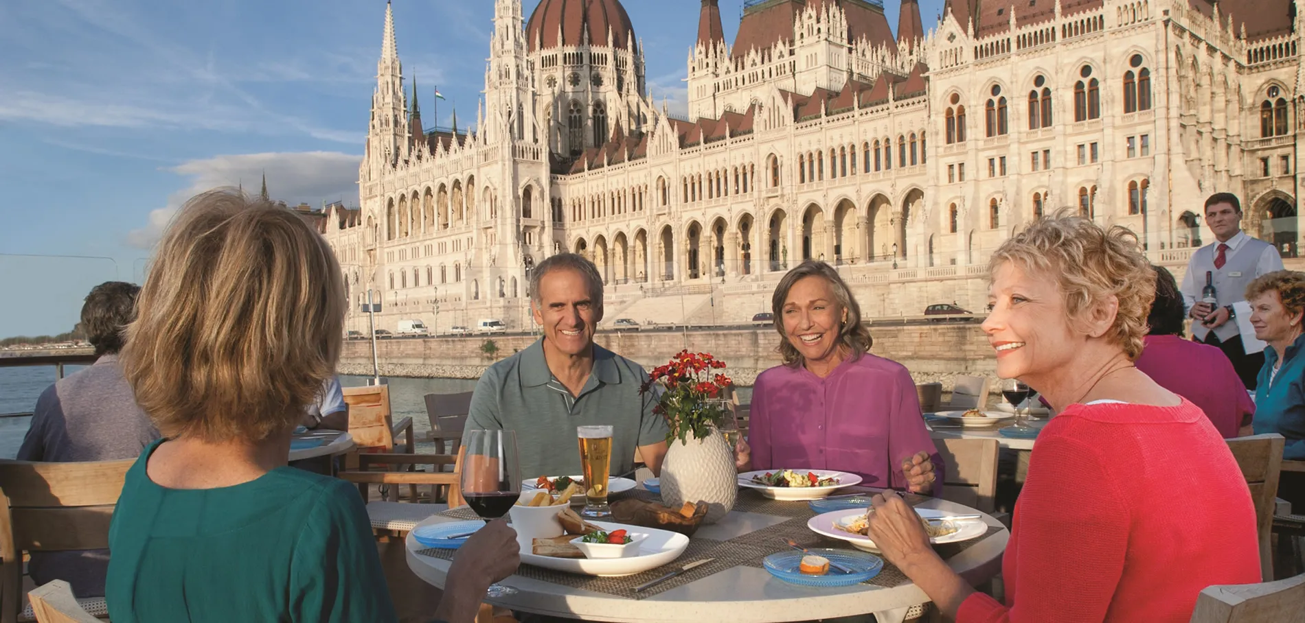 Friends dining outdoors with Hungarian Parliament Building in background