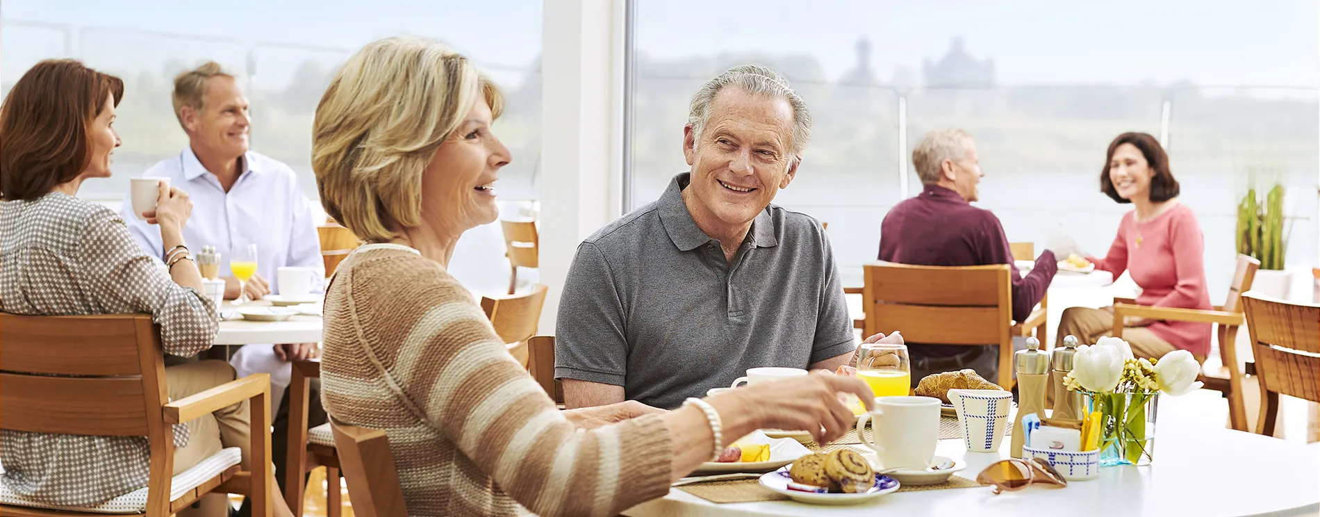 Seniors enjoying breakfast together at a bright, sunny cafe