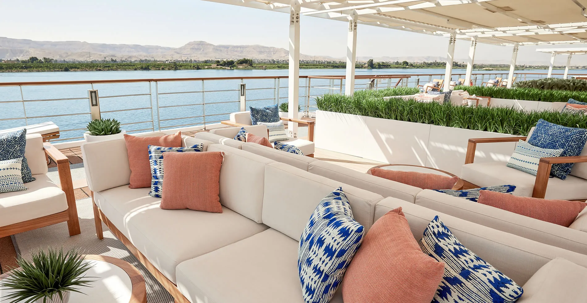 Luxurious river cruise deck with white sofas and blue and coral pillows
