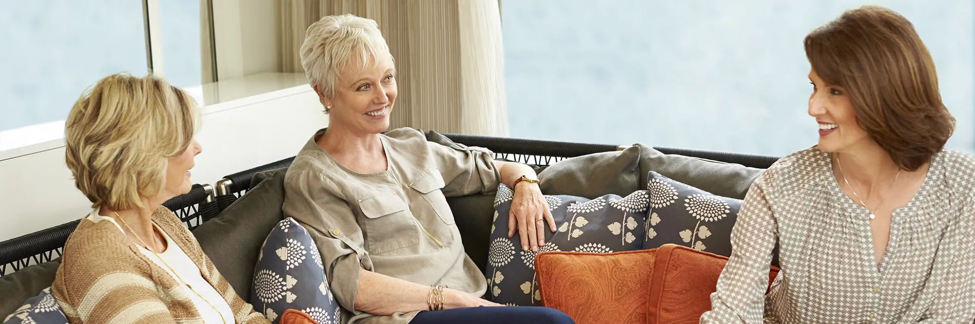 Three women sitting together on a couch, smiling and chatting