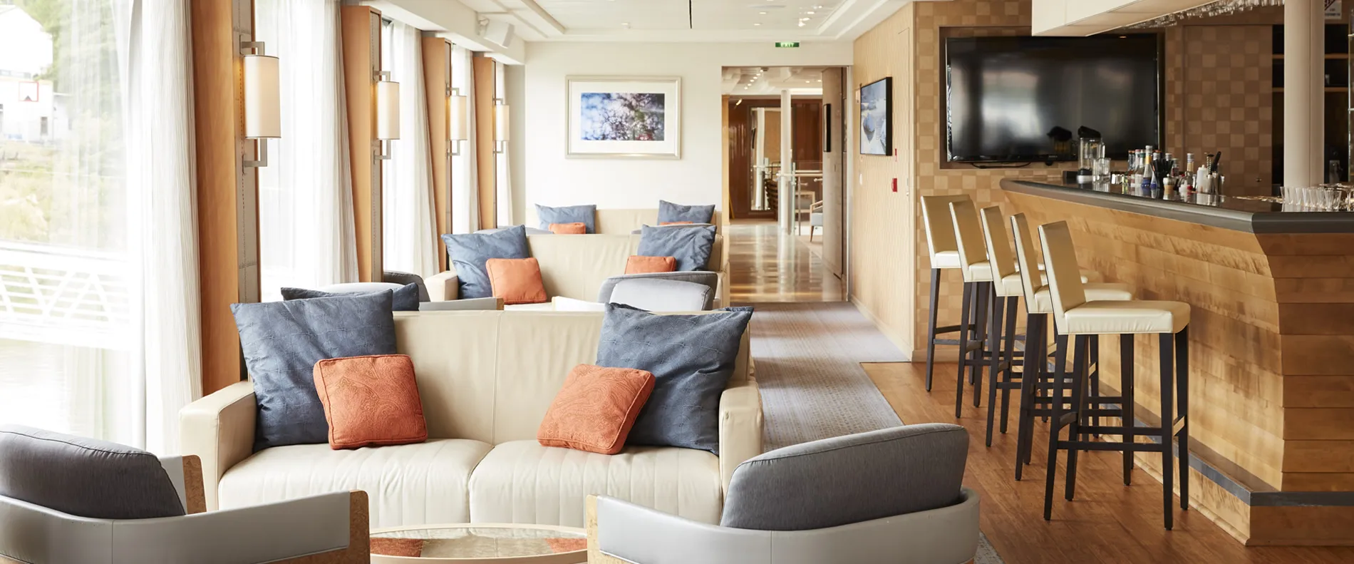 Modern lounge with white sofas, gray and orange cushions, bar area