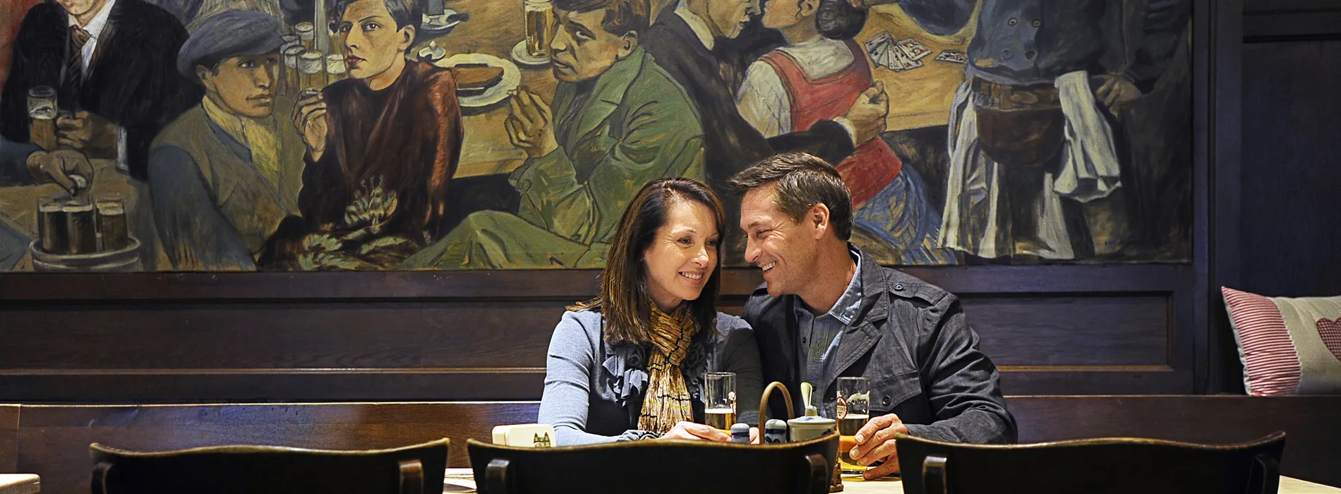 Couple enjoys drinks at cozy bar with vintage painting in background