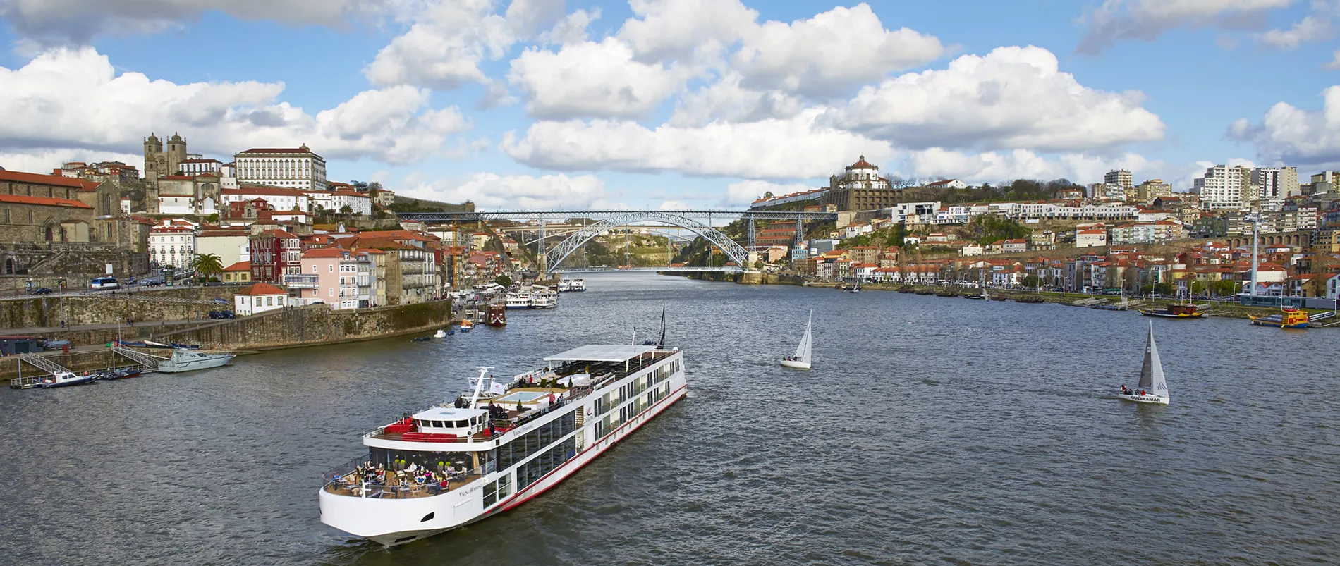Cruise ship and sailboats on Douro River with Porto's historic cityscape