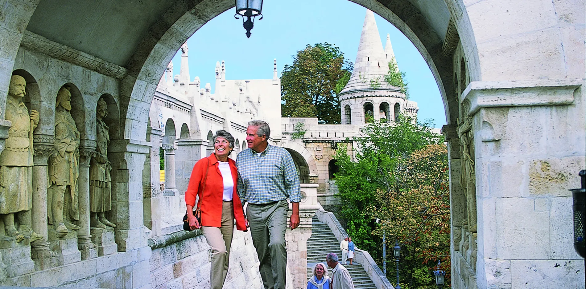 Tourists walking through historic stone archway at Fisherman's Bastion in Budapest