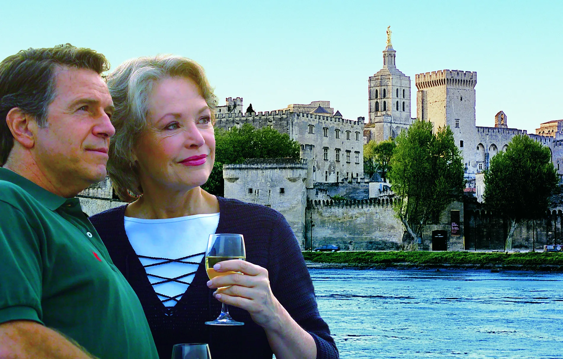 Couple enjoying wine with historic Papal Palace in Avignon, France background