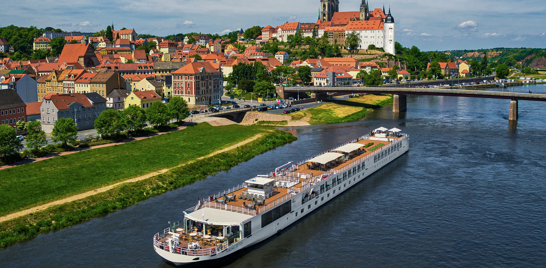 River cruise ship sailing through historic European town with red rooftops