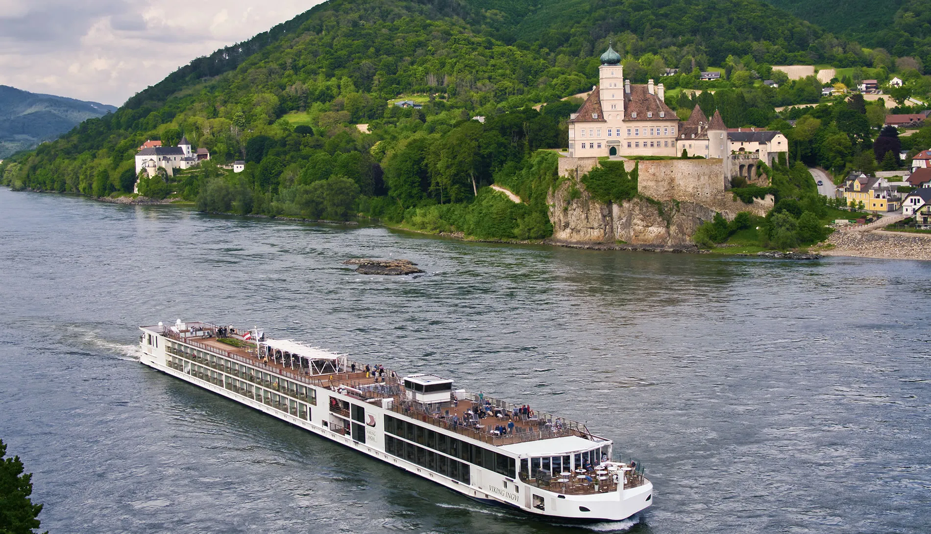 River cruise ship passing scenic castle on Danube River in Austria