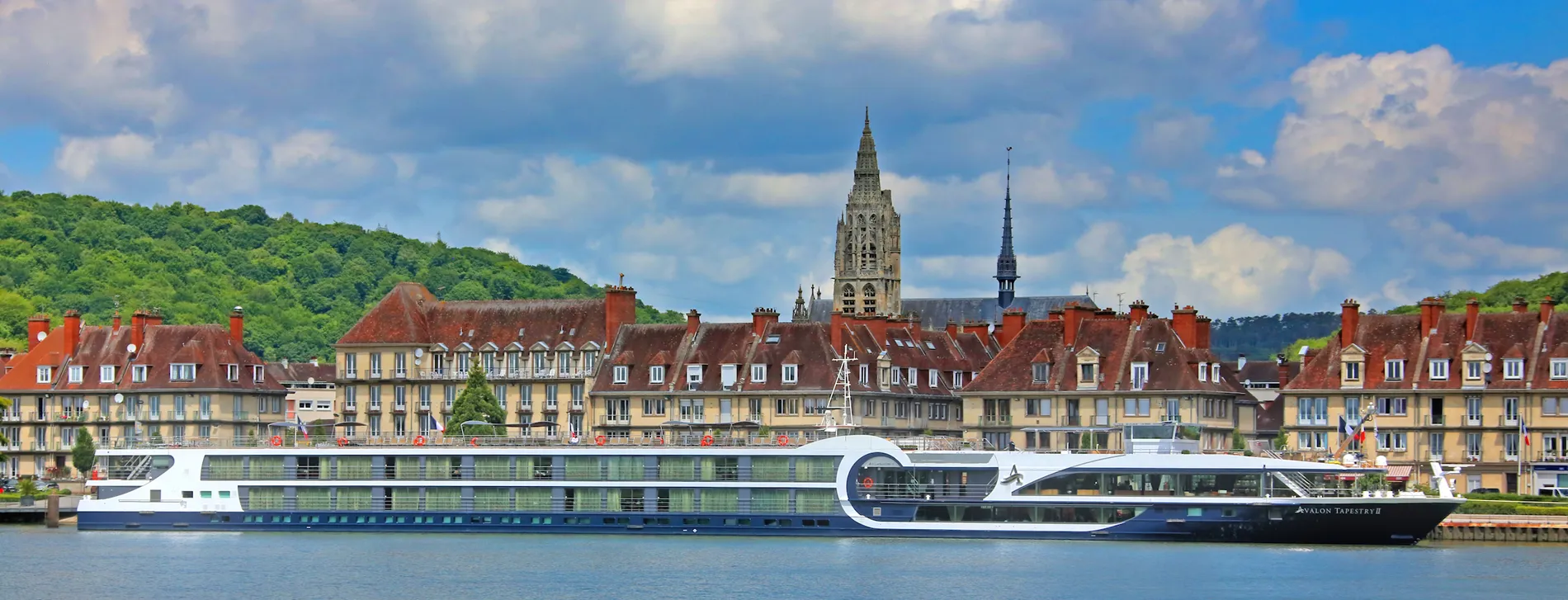 River cruise ship docked in front of historic French town with church spire