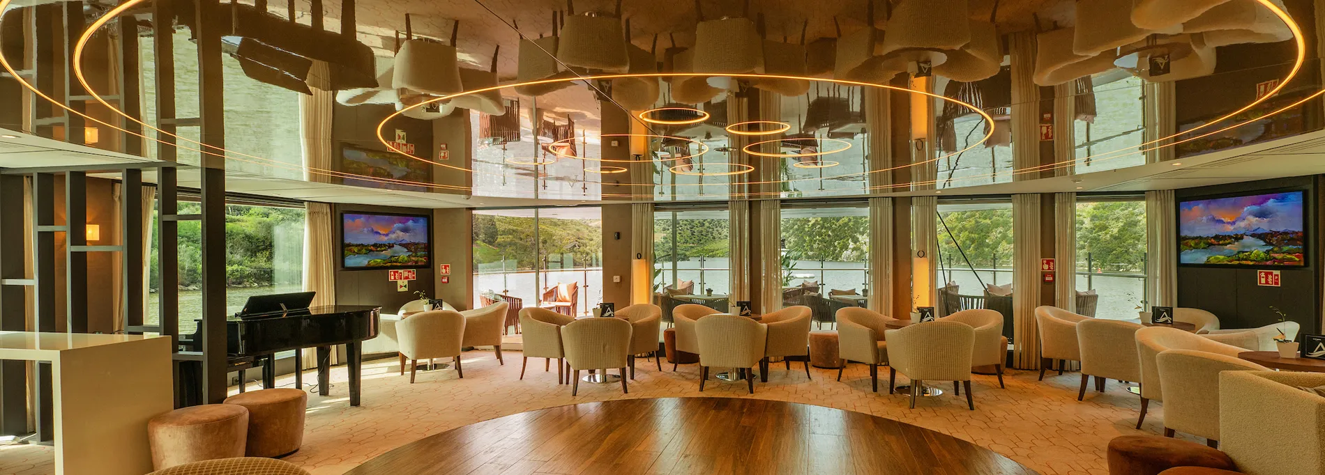 Elegant lounge with curved lighting, piano, and large windows overlooking nature