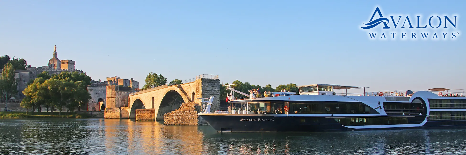 Avalon cruise ship docked near historic bridge and medieval fortress