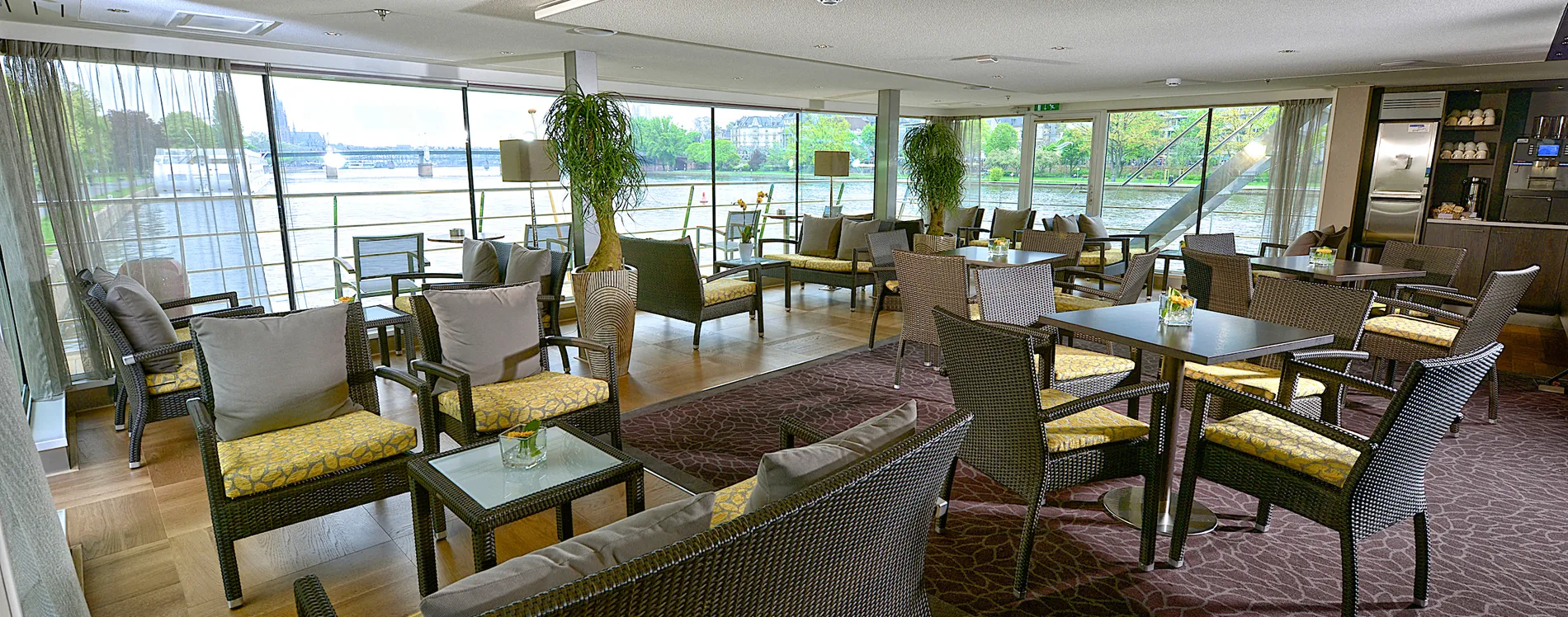 Elegant lounge area with river view, wicker chairs, and yellow cushions
