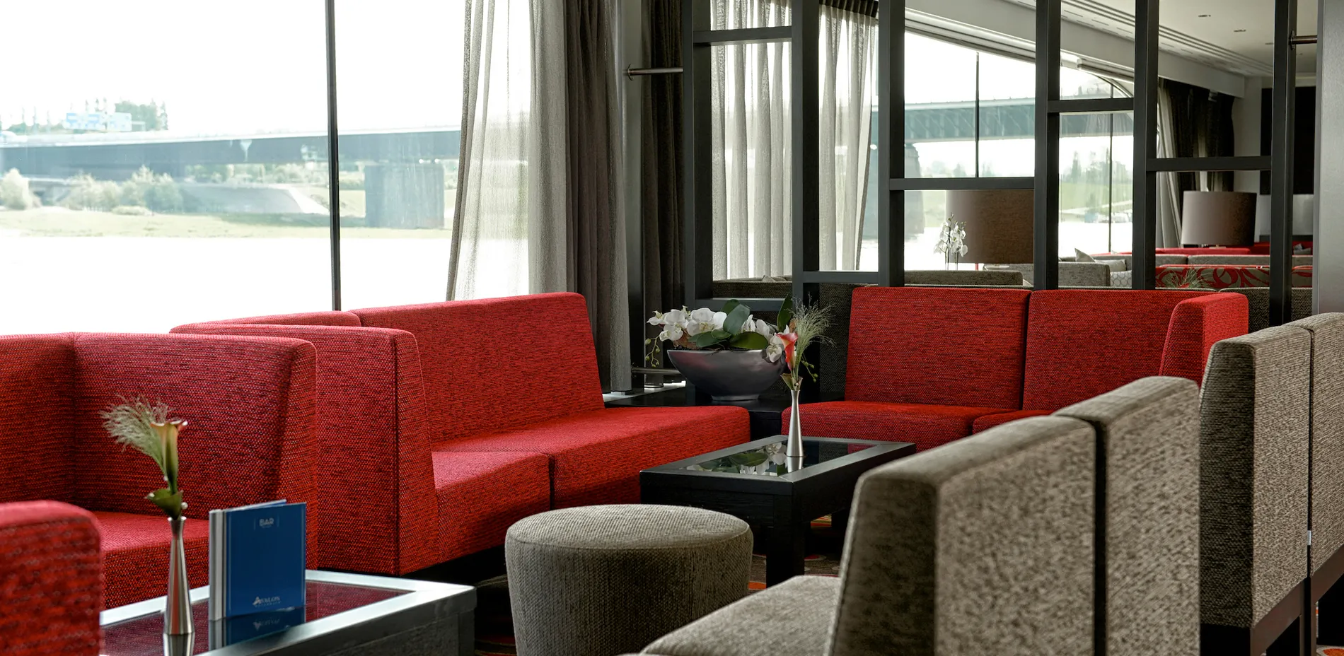 Modern lounge with red sofas, large windows, and minimalist decor