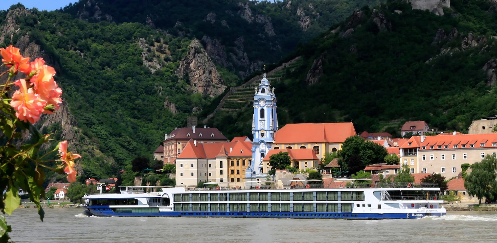 River cruise boat passing historic blue church in Danube riverfront town