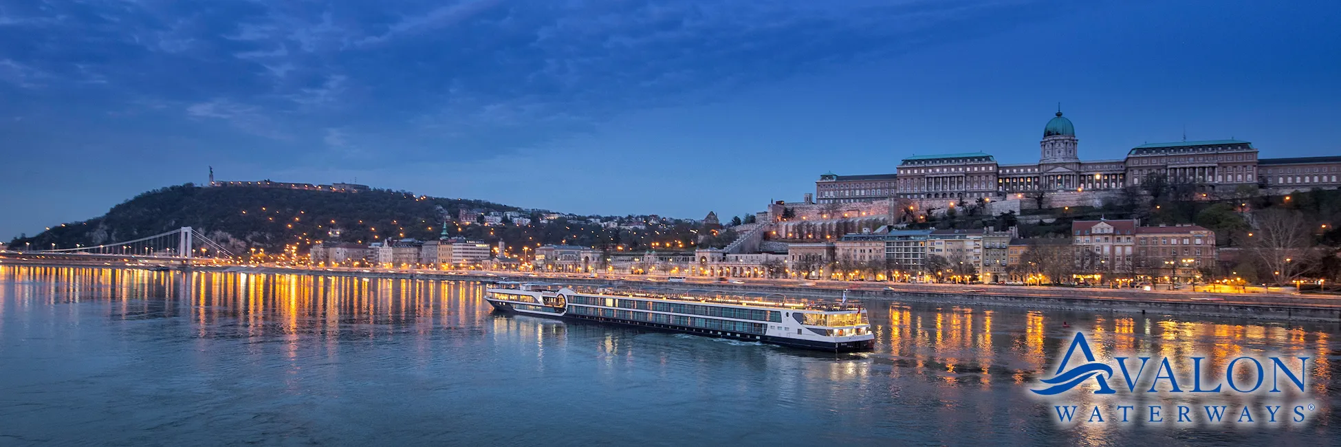 Illuminated Budapest skyline with cruise ship on Danube River at twilight