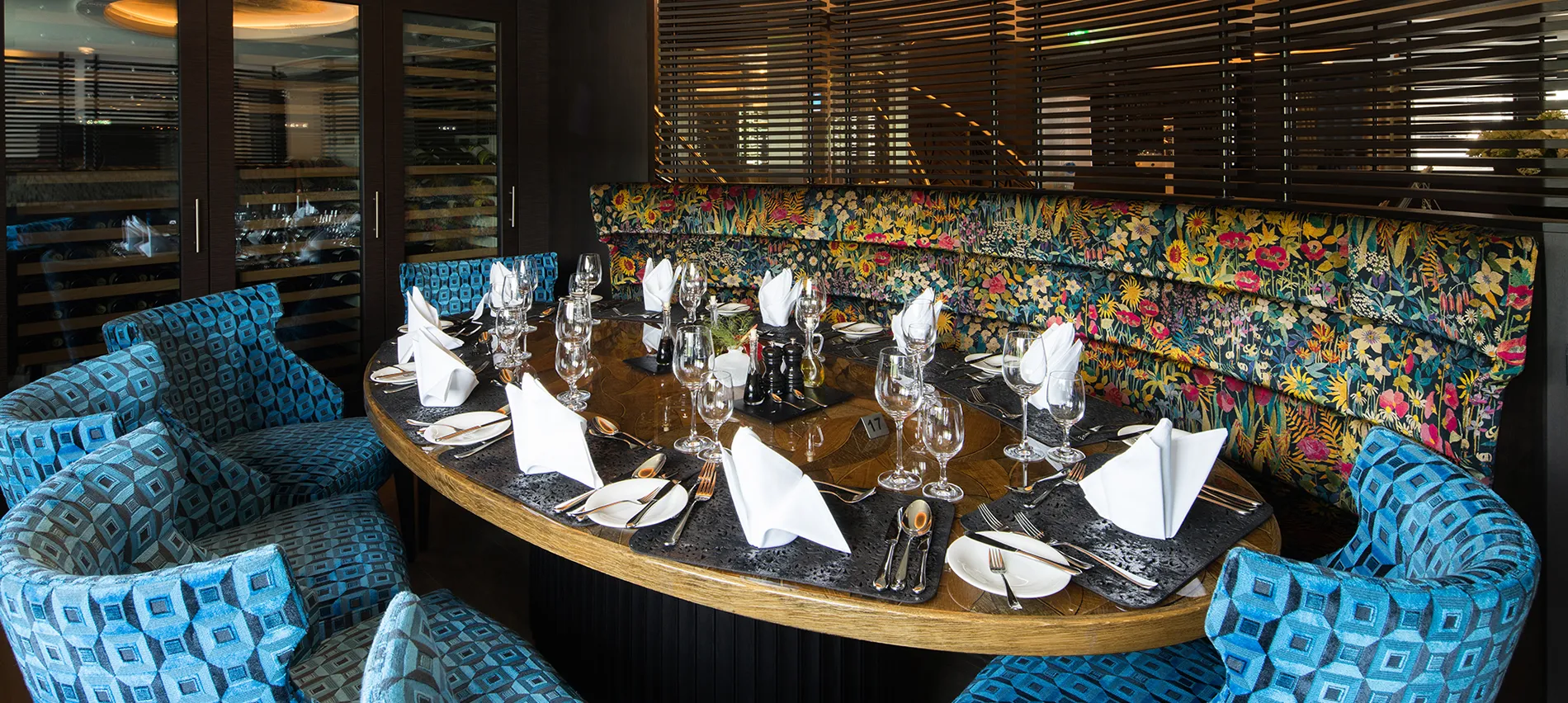 Elegant restaurant table setting with blue chairs and floral wallpaper