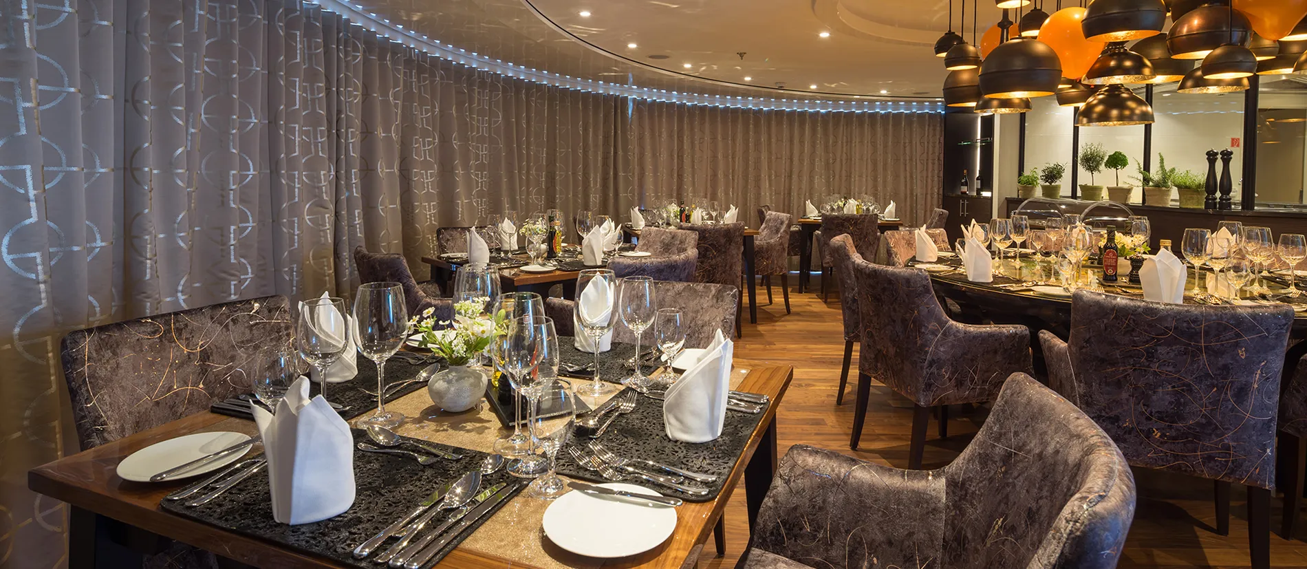 Elegant restaurant dining room with set tables, plush chairs, and soft lighting