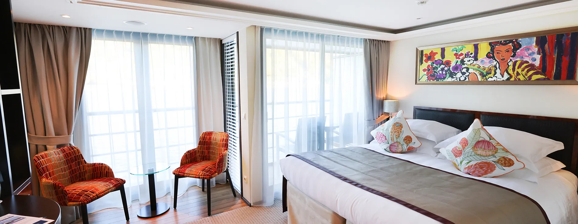 Bright hotel room with colorful chairs, art, and large windows