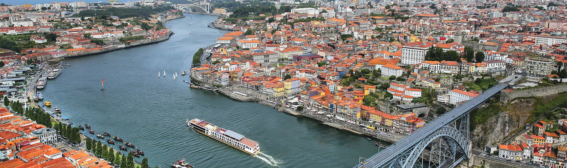 Aerial view of Porto, Portugal, showing river, boats, and historic orange-roofed buildings