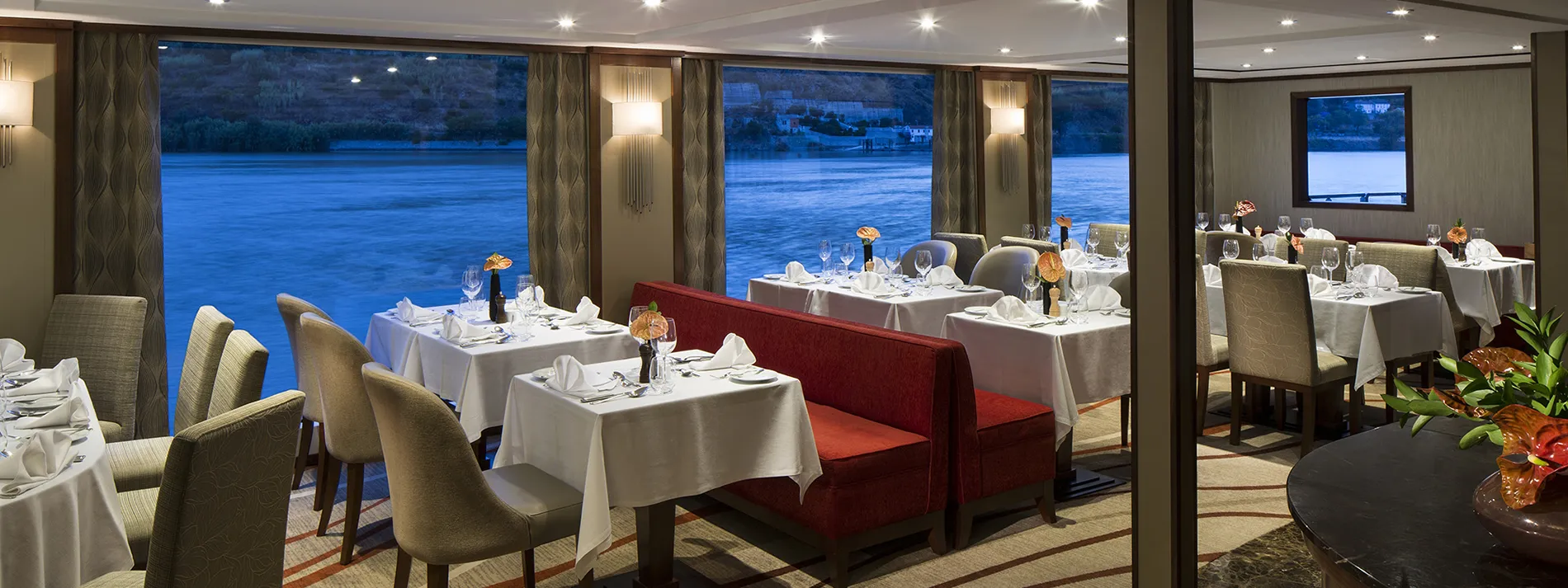 Elegant dining room on a cruise ship with river view at dusk