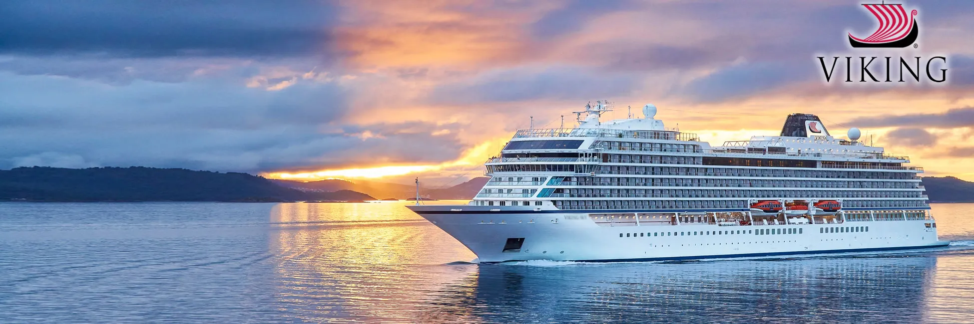 Viking cruise ship sailing at sunset with dramatic sky and mountain backdrop