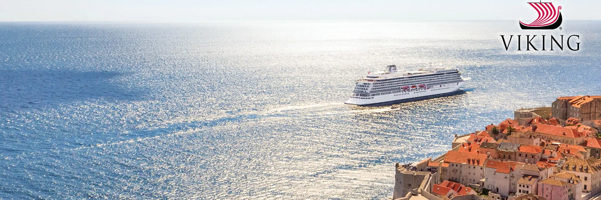 Viking cruise ship sailing near coastal town with red-tiled roofs
