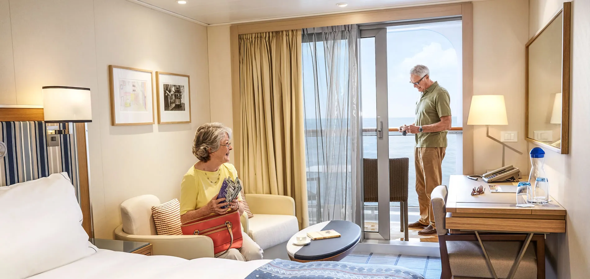 Elderly couple in cruise ship cabin with ocean view, relaxing together