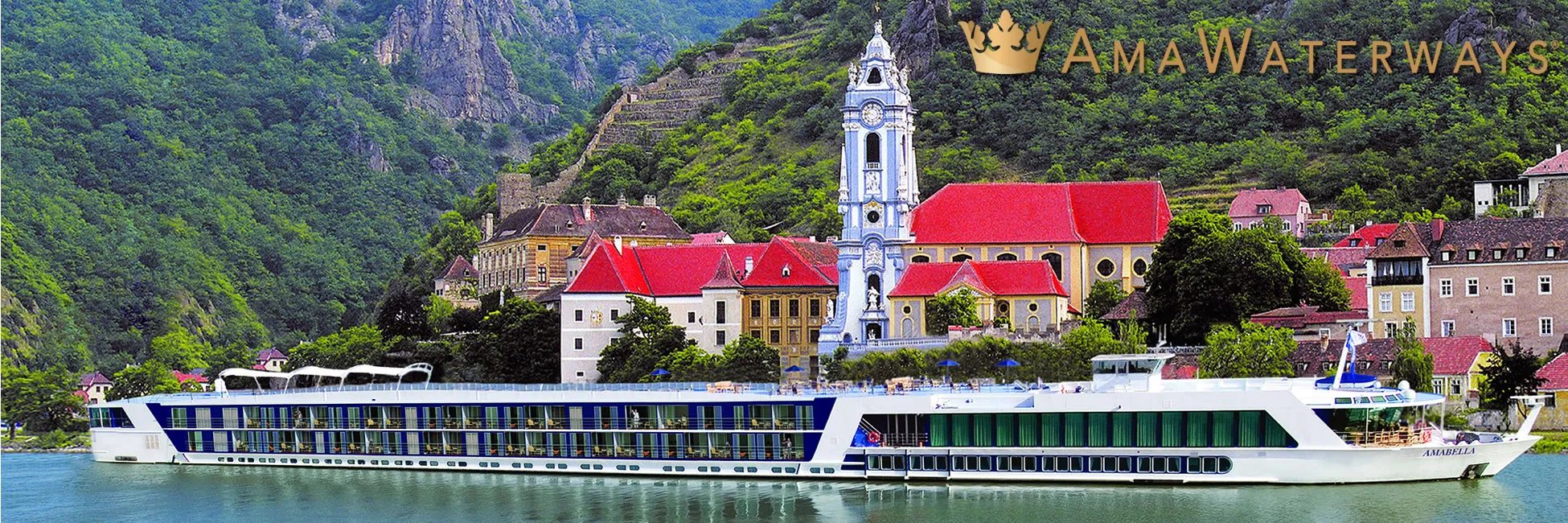 AmaWaterways river cruise ship docked by historic European town with mountain backdrop