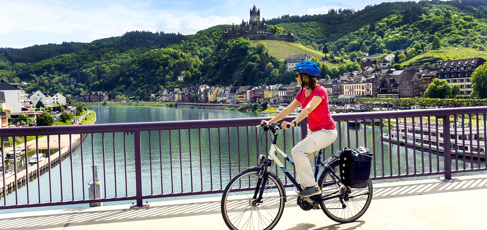 Cyclist on bridge overlooking Cochem Castle and Moselle River in Germany