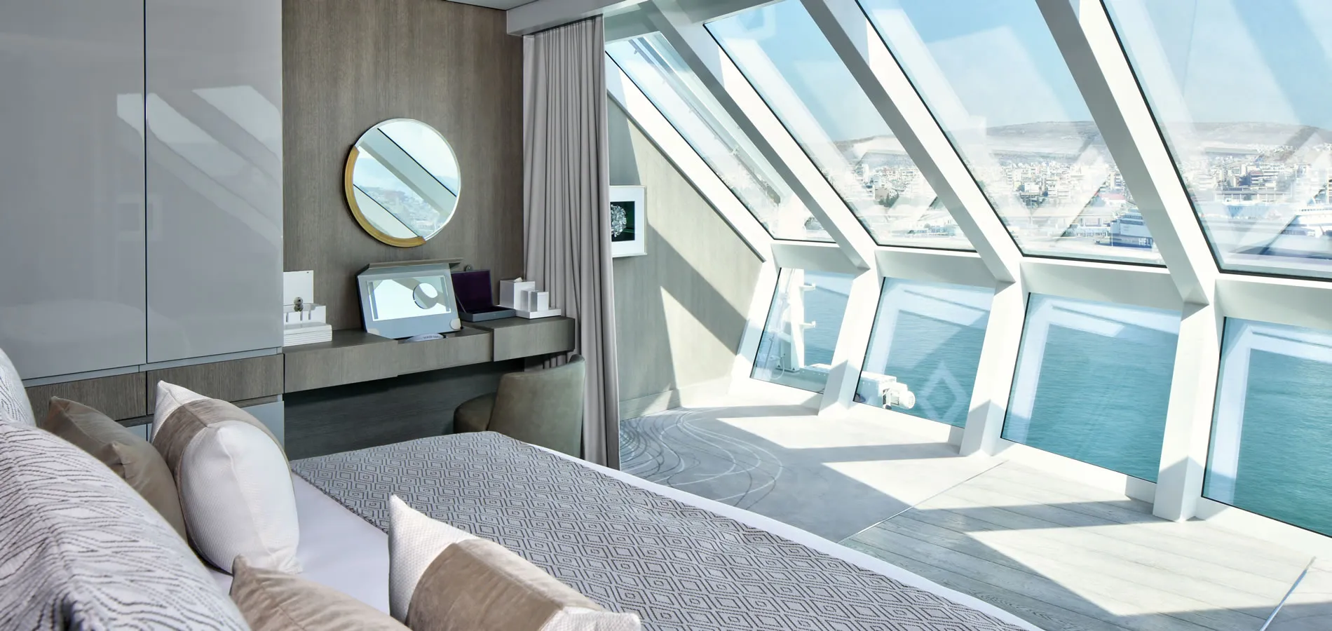 Modern bedroom with large windows overlooking ocean and cityscape